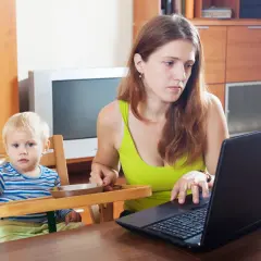 Pracująca mama z dzieckiem przy stole. Widać, ile jest macierzyńskiego w codziennym życiu, gdy trzeba pogodzić pracę z opieką.