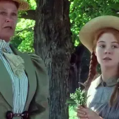 Charakterystyka Ani z Zielonego Wzgórza: Marilla i Ania w słomkowych kapeluszach, wśród drzew. Ania trzyma konwalie.