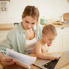 Kobieta z dzieckiem przy laptopie, szuka informacji o tym, urlop rodzicielski ile płatny.