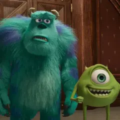 Sully i Mike, bohaterowie fajnych bajek, stoją obok siebie. Sully wygląda na zmartwionego, a Mike uśmiecha się szeroko.