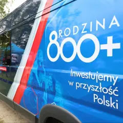 Niebieski van z napisem "RODZINA 800+" i hasłem "Inwestujemy w przyszłość Polski". Obok rodziny, symbolizującej wsparcie, choć niektórzy mogą postrzegać to jako likwidację 800 plus.
