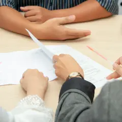 Dwie osoby przeglądają dokumenty, być może w celu uzyskania zgody na wyjazd dziecka za granicę.