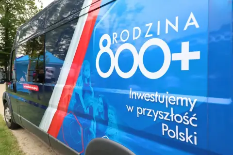 Niebieski van z napisem "RODZINA 800+" i hasłem "Inwestujemy w przyszłość Polski". Obok rodziny, symbolizującej wsparcie, choć niektórzy mogą postrzegać to jako likwidację 800 plus.