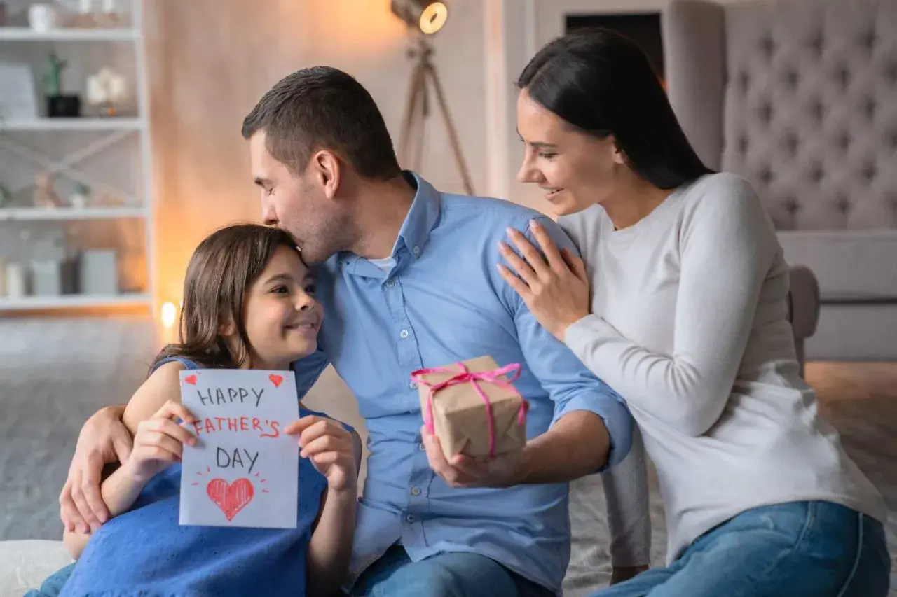 Córka daje tacie kartkę z napisem "Happy Father's Day", a mama obejmuje ich. To piękny wiersz o rodzinie i miłości.